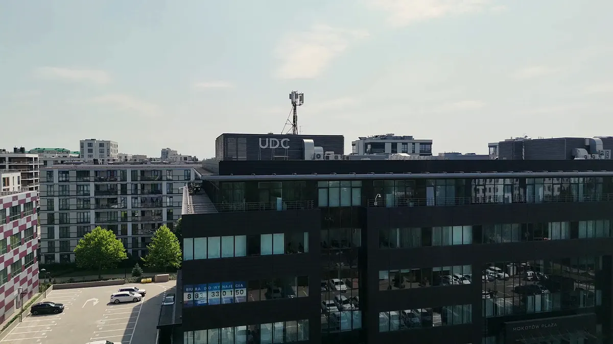 Budynek przy Postępu 6 z lotu ptaka, ze znakiem UDC na dachu, w otoczeniu biurowców Służewca