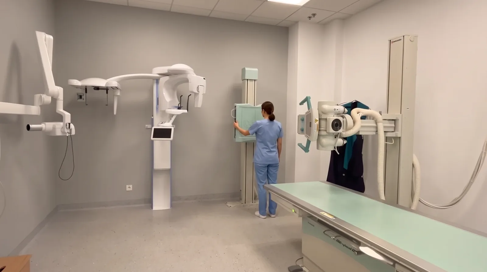 Pracownia RTG UDC: statyw ścienny z detektorem, lampa i stół, technik przy aparacie