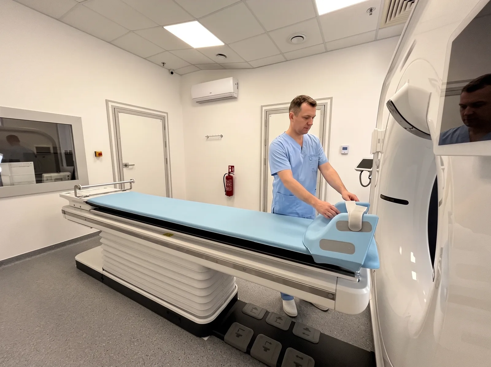 Pracownia tomografii komputerowej UDC: stół badania i gantry, technik przygotowuje stanowisko