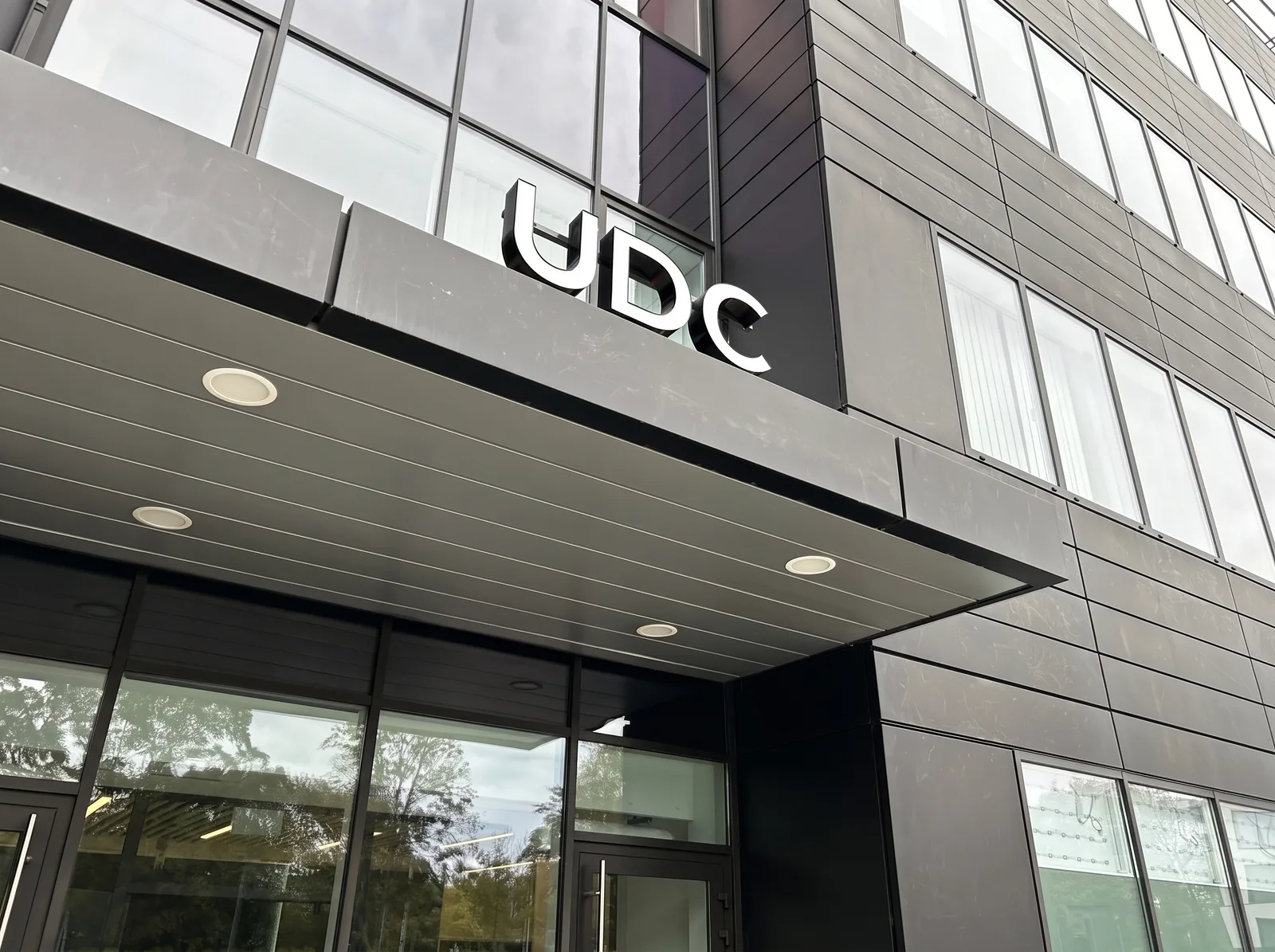 Wejście do budynku przy Postępu 6 ze znakiem UDC nad drzwiami